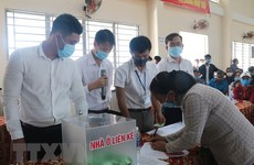 Các hộ dân thuộc diện phải giải tỏa, di dời ký nhận đất tái định cư đã bốc thăm. Ảnh: TTXVN