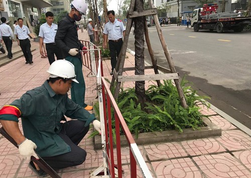 Lực lượng chức năng phá dỡ rào chắn bằng sắt dựng trên vỉa hè chung cư Vinaconex 7. 