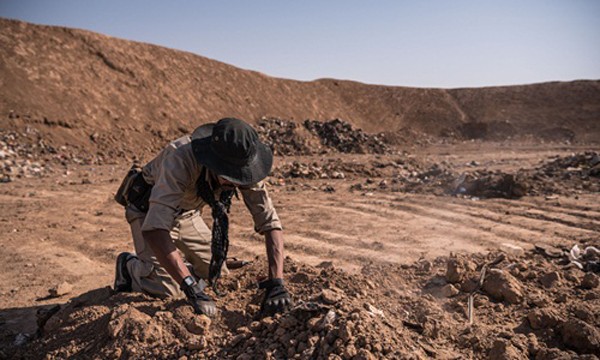 Một người lính đang đào bới, tìm kiếm xác chết trong một mồ chôn tập thể ở Iraq. Ảnh:New York Times