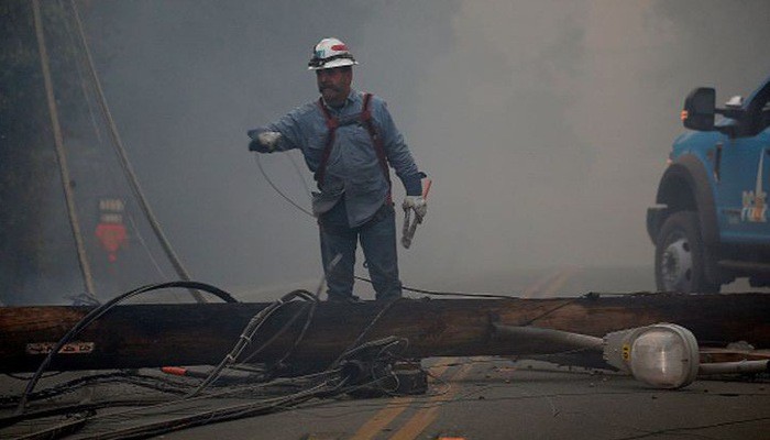 Một công nhân của PG&E đang xử lý một cột điện bị đổ trong đám cháy Camp Fire hôm 8/11/2018 - Ảnh: Getty/CNBC.