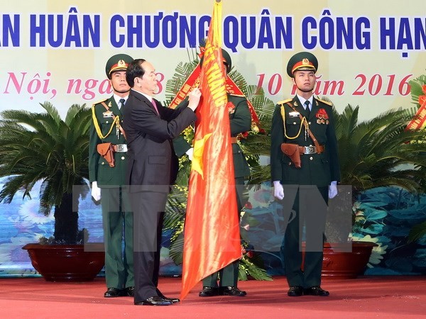 Chủ tịch nước Trần Đại Quang gắn Huân chương Quân công hạng Nhất lên lá cờ truyền thống của lực lượng vũ trang Thủ đô. (Ảnh: Nhan Sáng/TTXVN)